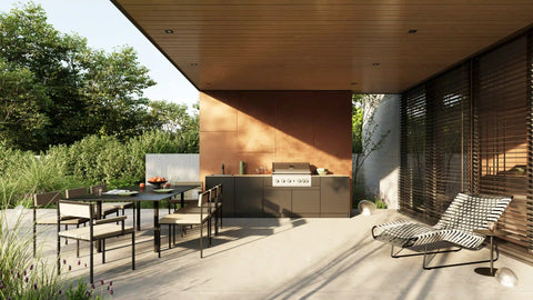 Modern outdoor kitchen under a wooden canopy with dining table and sun lounger.