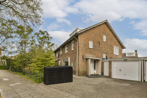Zwarte vuilnisbakkenbox van BIO Stefan voor een bakstenen huis in een woonwijk.