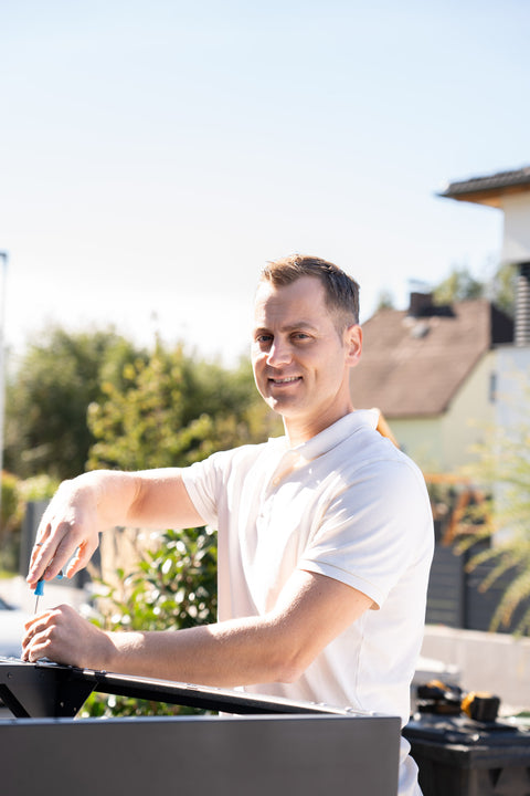 Un homme installe une BIO Stefan Mülltonnenbox dans le jardin.