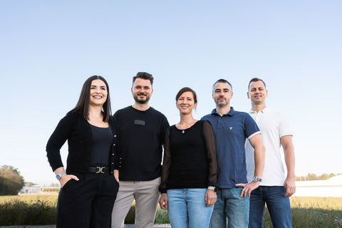 A group of five people is standing outside, smiling.