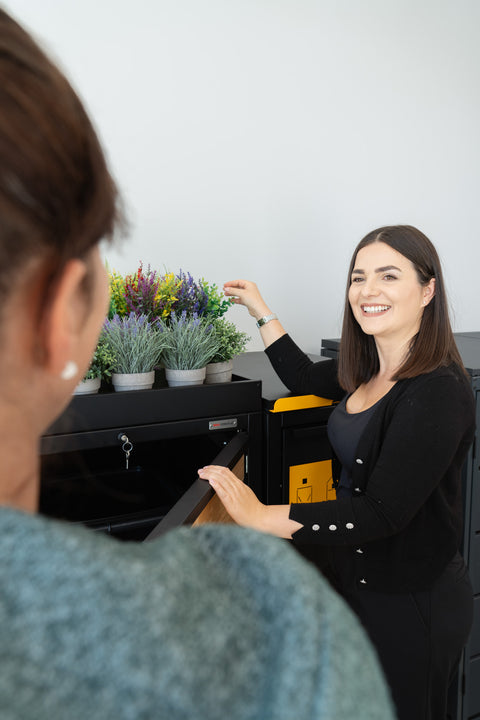 Woman shows Bio Stefan trash bin box with plants on the lid.