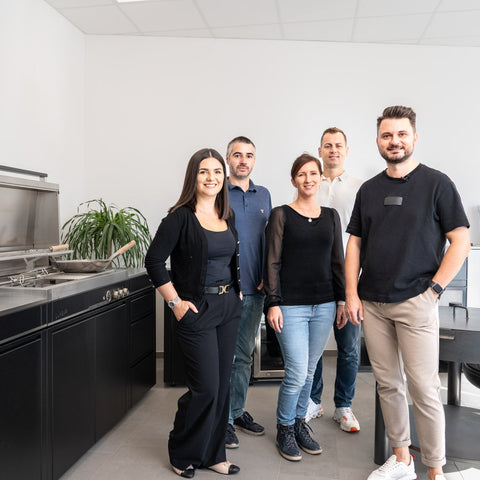 Group of five people standing in a modern outdoor kitchen by Bio Stefan.
