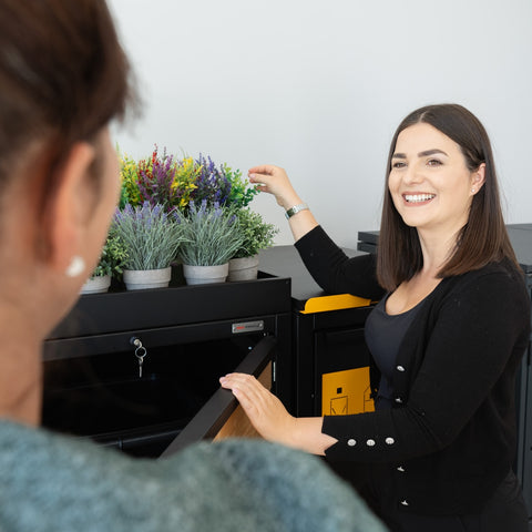 A woman smiles next to a Bio Stefan trash bin box with plants on it.