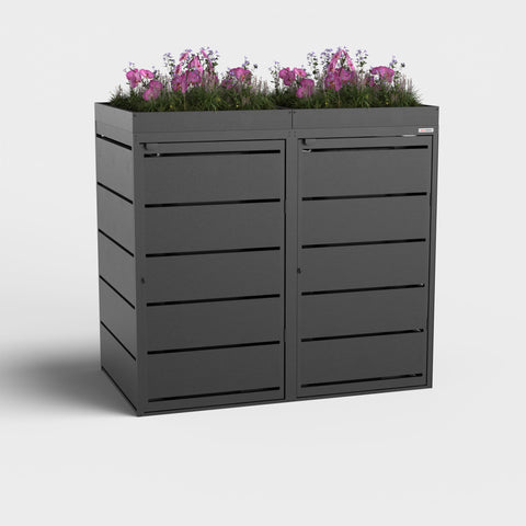 Box pour poubelles noire de BIO Stefan avec toit végétalisé et fleurs.