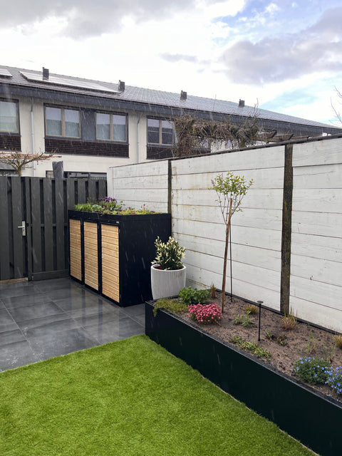 Holzmichl trash bin boxes next to planted beds in the modern outdoor area.