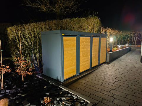 Holzmichl garbage bin box at night in the garden with lighting.