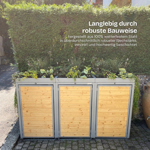 Cassonetto per bidoni in acciaio resistente alle intemperie, decorato con piante, davanti a una siepe verde.