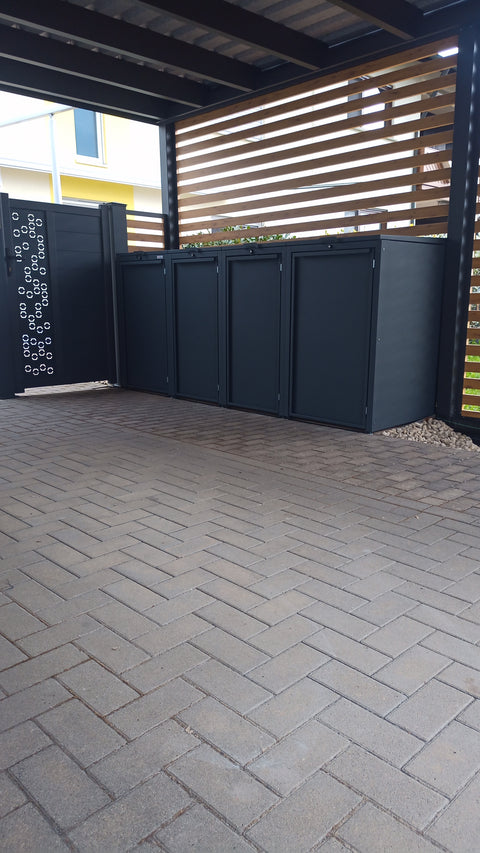 Patru cutii negre pentru tomberoane de gunoi de la BIO Stefan sub o copertină.