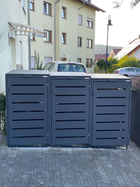 BIO Stefan Alubert Mülltonnenbox 3er 240l in Anthrazit mit angehobenem Schrägdeckel vor Hausfassade