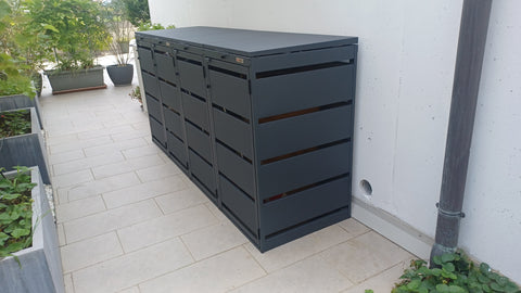 BIO Stefan Dagobert Mülltonnenbox 4er 120l in Anthrazit steht rechts an weißer Hauswand auf heller Terrasse