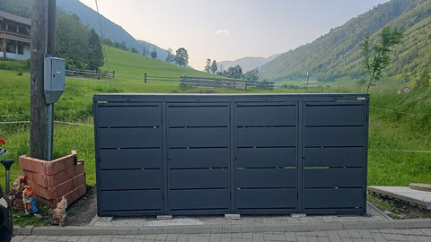 BIO Stefan Mülltonnenbox Dagobert 4er 240l in Anthrazit vor grüner Wiese und Berglandschaft