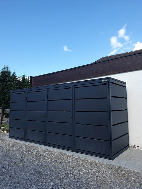 BIO Stefan Mülltonnenbox Dagobert 4er 240l in Anthrazit steht seitlich am Haus auf Kiesweg