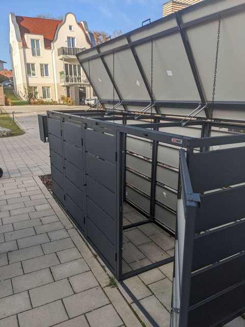BIO Stefan Dagobert Mülltonnenbox 4er 240l in Anthrazit, geöffnet auf Gehweg vor Wohnhaus