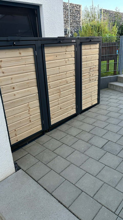 BIO Stefan Holzmichl Mülltonnenbox 3er 120l und 240l in Anthrazit seitlich an der Hauswand vor Gabionenwand und Doppelstabmattenzaun