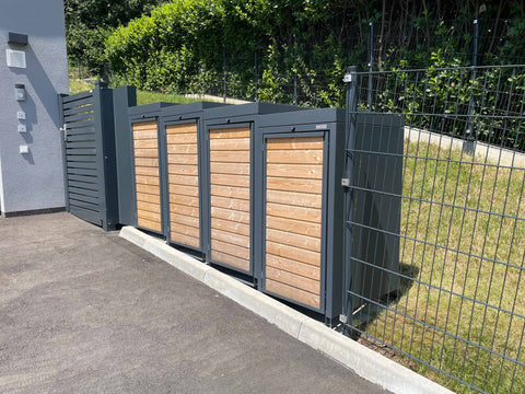 BIO Stefan Holzmichl Mülltonnenbox 4er 120l, anthrazit mit Holzfront und Pflanzdach-Gefälle neben Zaun