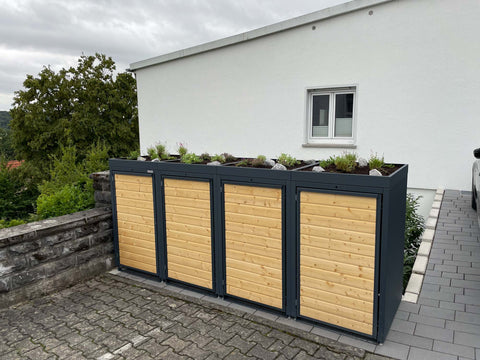 BIO Stefan box pour poubelles Holzmichl 4 bacs 240l en anthracite avec façade en bois et toit végétalisé devant la maison