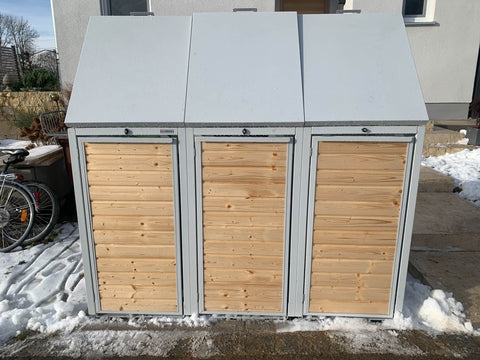 BIO Stefan Holzmichl Mülltonnenbox 3er 120l in Reinweiß RAL 9010 frontal an der Hauswand mit drei geschlossenen Holztüren und abgeschrägten Klappdeckeln