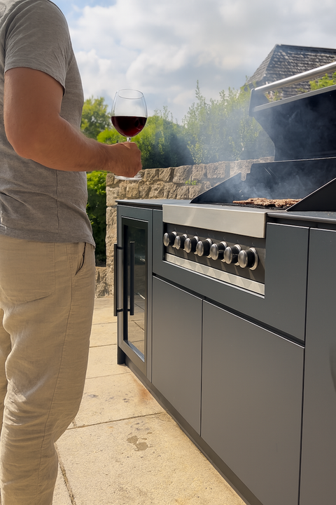 Person stands with a glass of wine next to a modern outdoor kitchen from BIO Stefan.