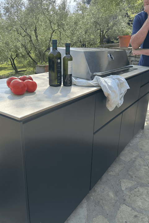 Outdoor kitchen by BIO Stefan with tomatoes and olive oil next to the grill in the garden.